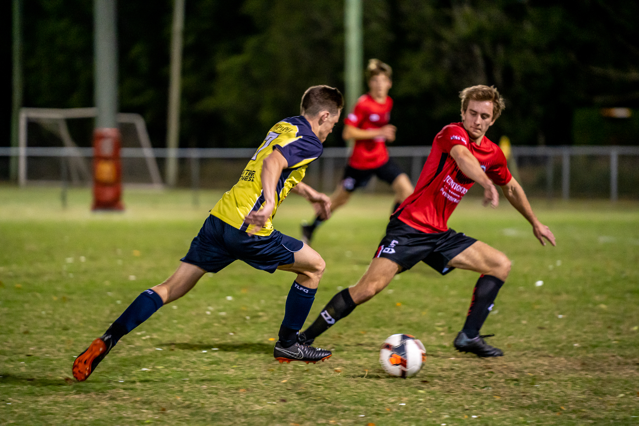 Two footballers competing for the ball during a local match