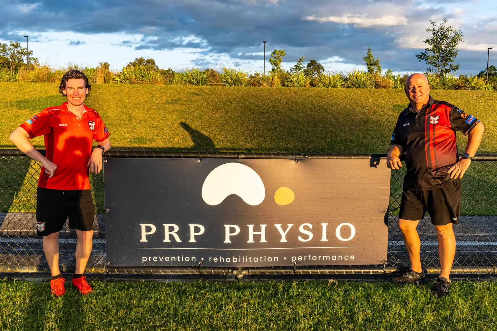 Nathan Ashby beside a PRP Physio sponsor banner at a local football ground