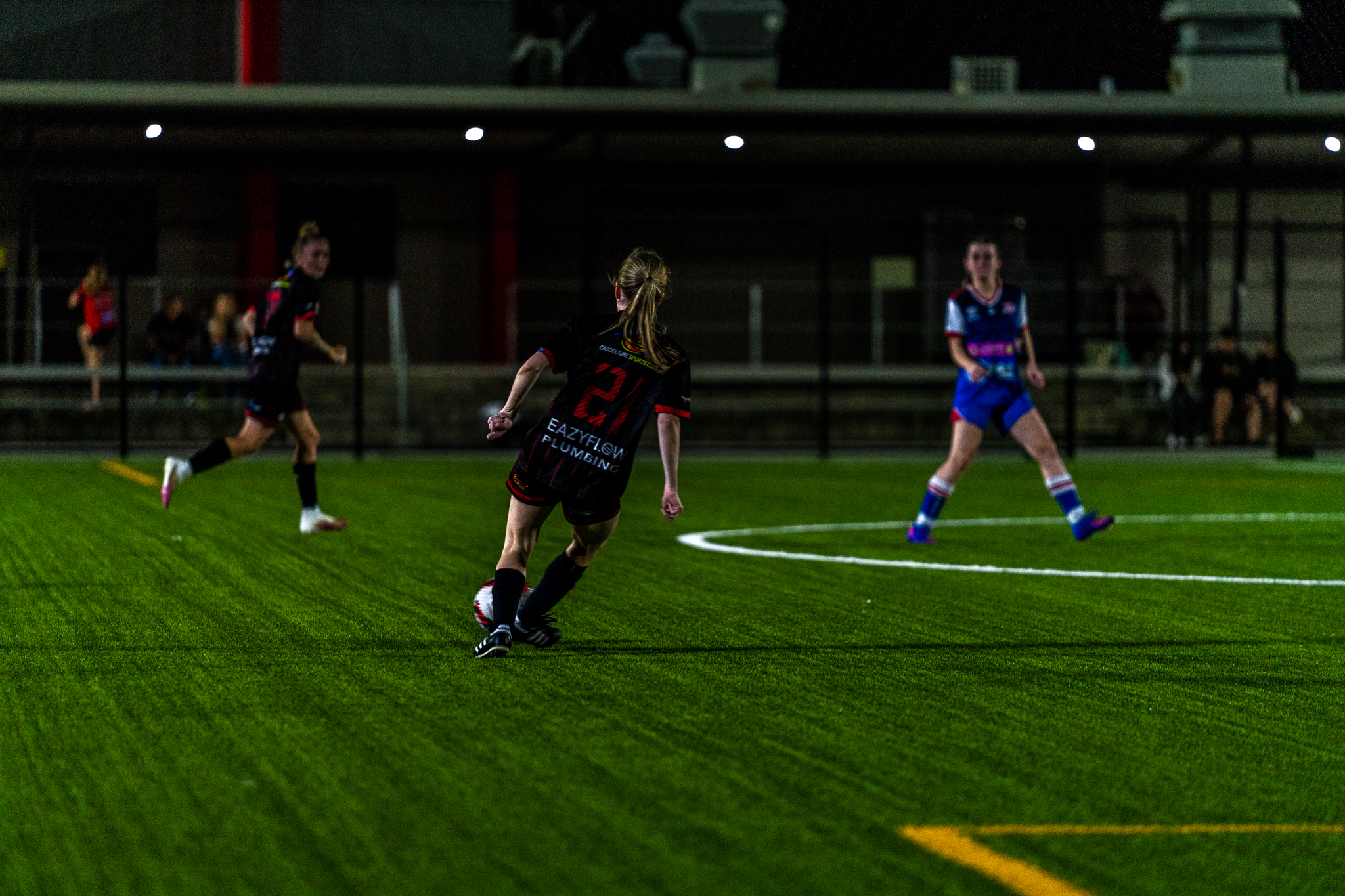 Women's football match on a synthetic pitch at night