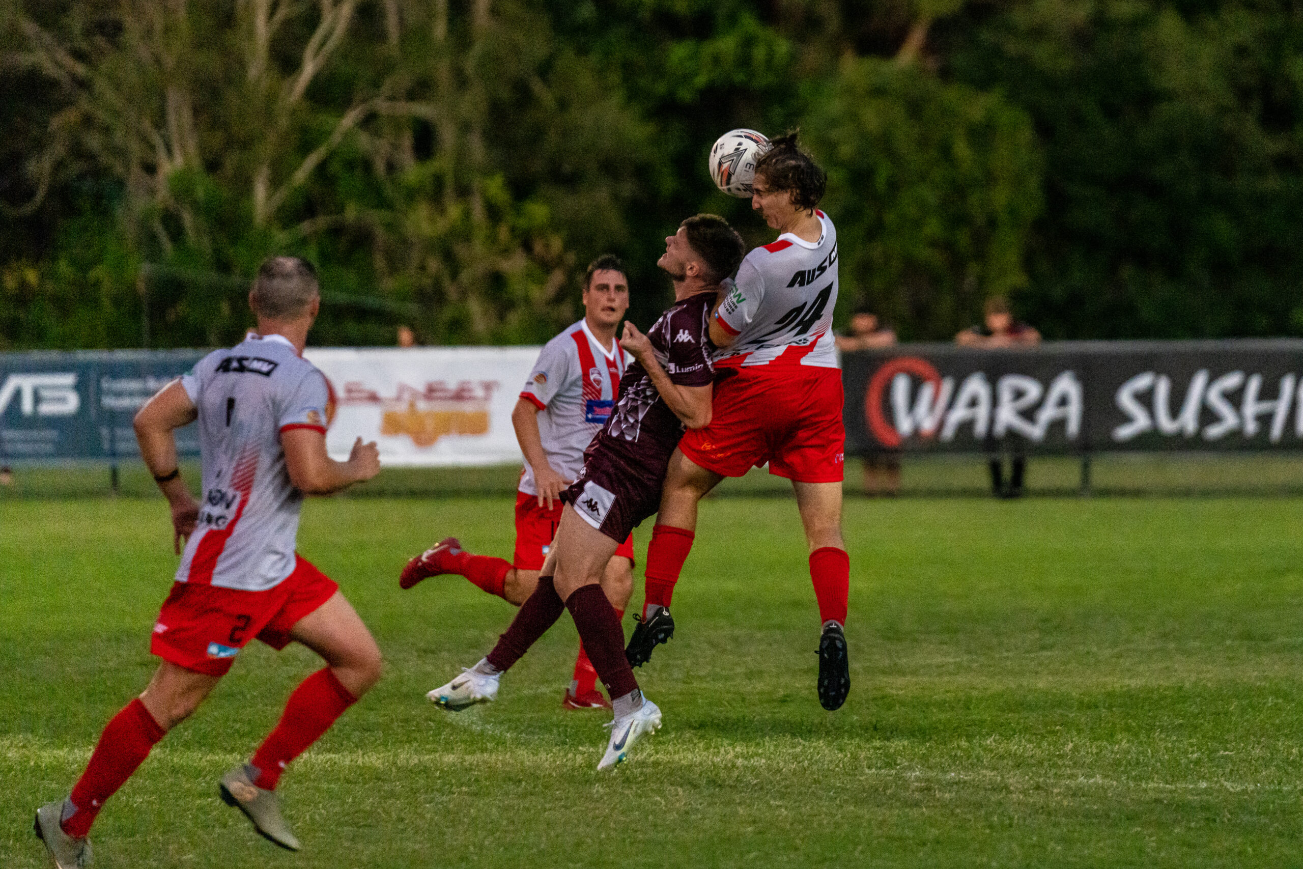 Footballers contesting a header during a local match