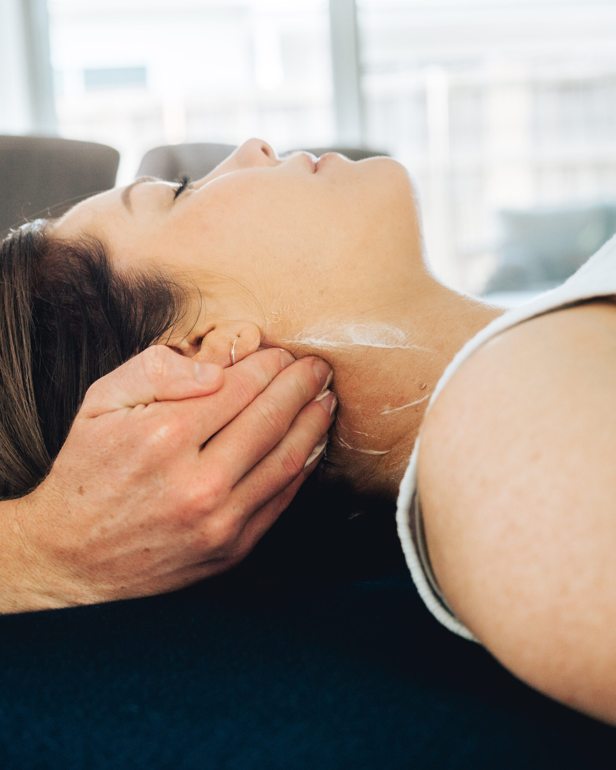 A woman receiving a physiotherapy massage on her neck from a sports physiotherapist.