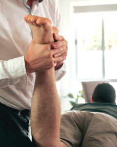 Physiotherapist assessing a client's hip and knee movement on a treatment table
