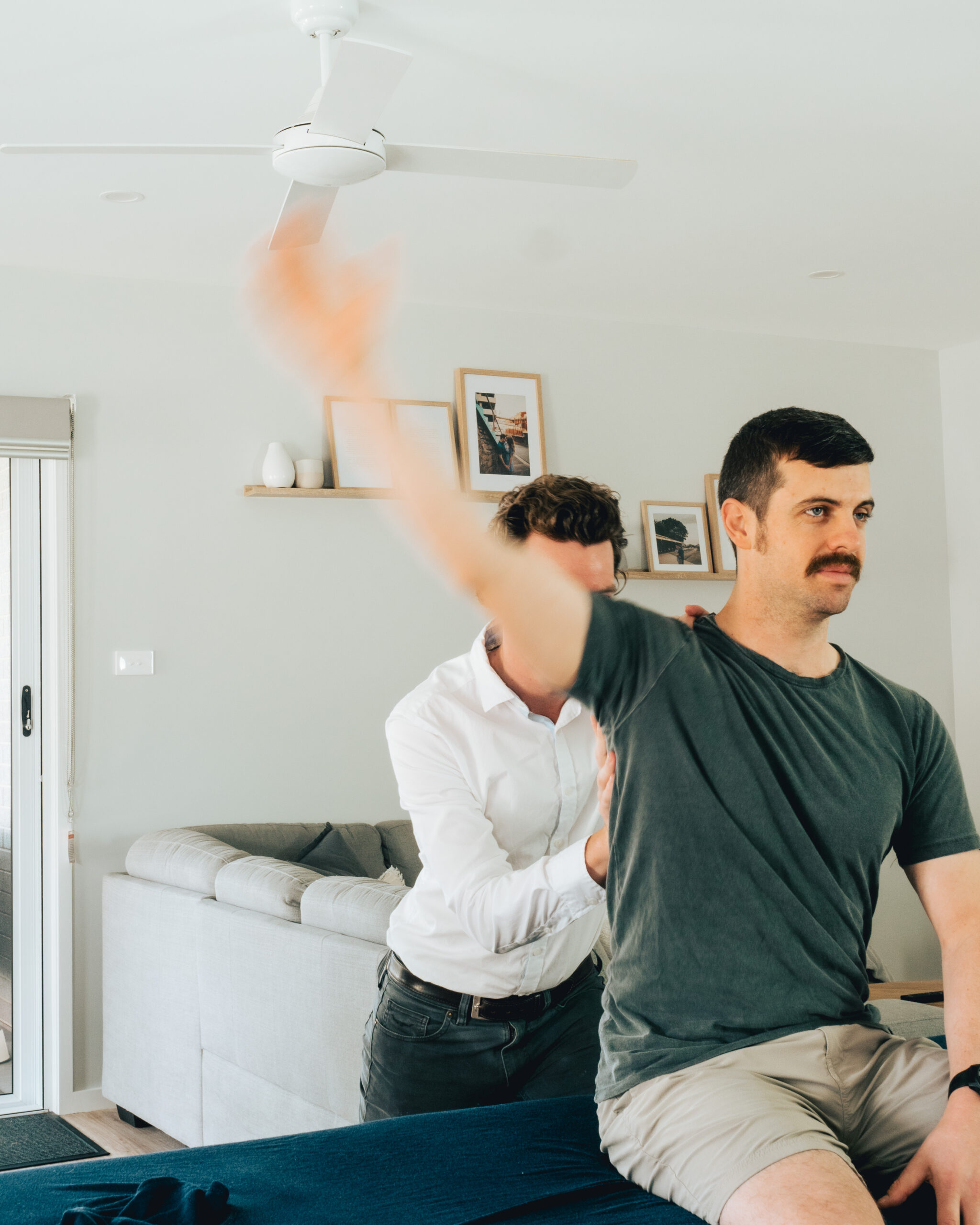 A man is receiving sports physiotherapy on a couch with his arms outstretched.