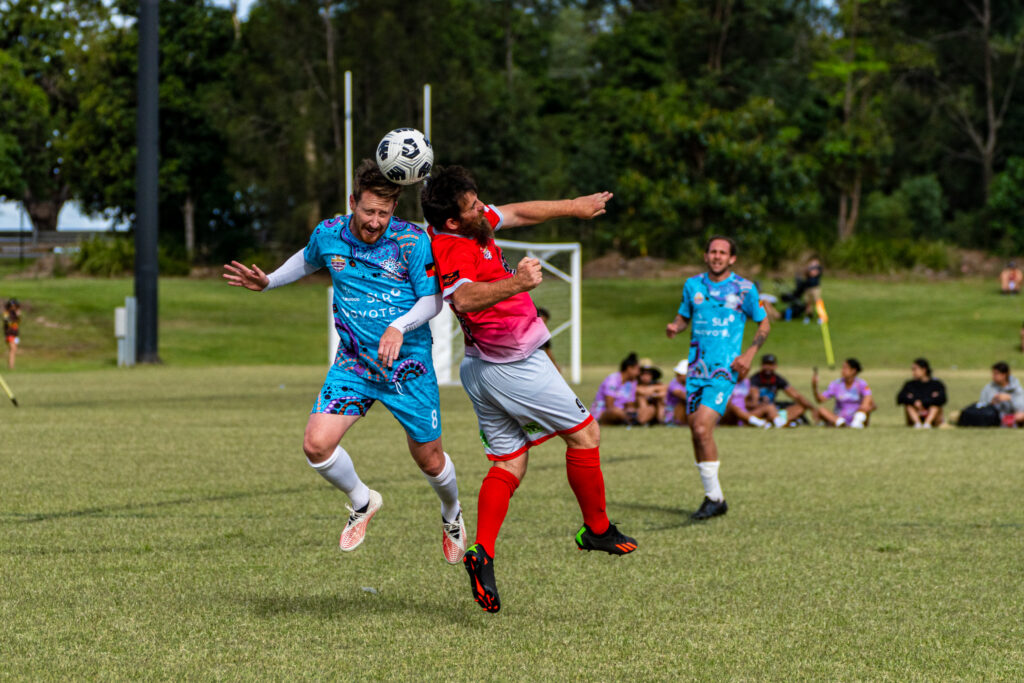 Footballers challenging for a header during a local match